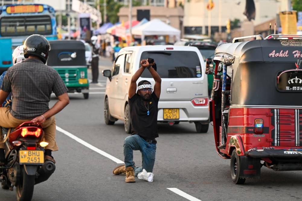A protestor kneels down along in an ongoing anti-government demonstration outside the President's office in Colombo on April 27,2022, demanding the resignation of President Gotabaya Rajapaksa over the country's crippling economic crisis. - AFP