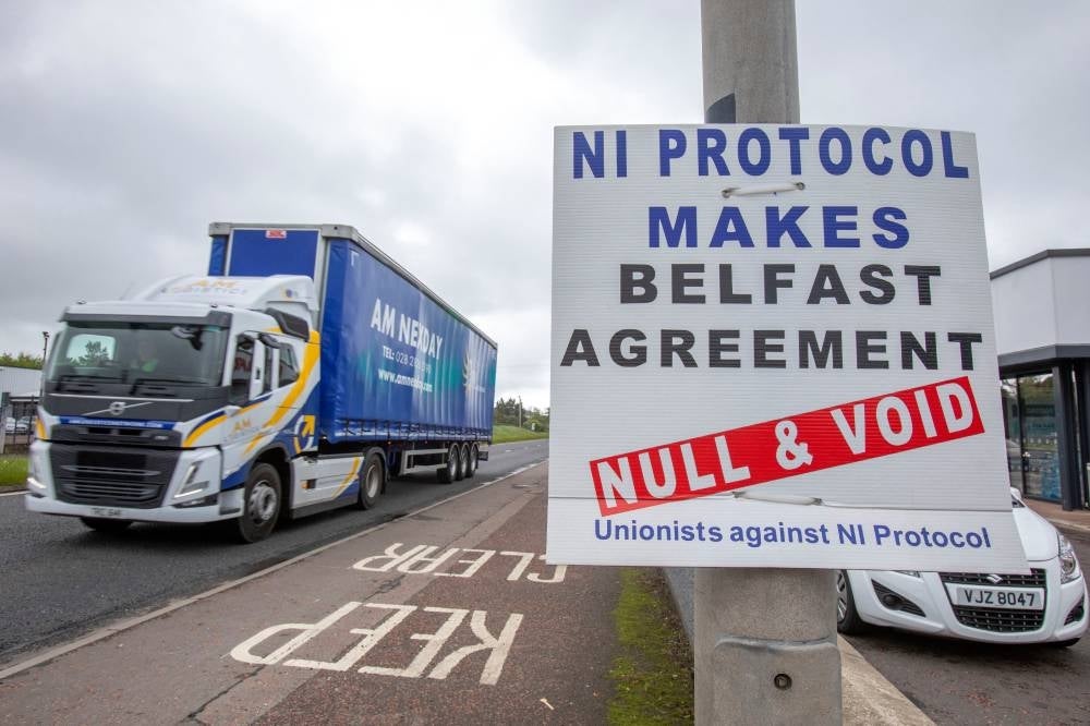 A lorry passes an anti 'Northern Ireland Protocol' sign as it is driven away from Larne port, north of Belfast in Northern Ireland, after arriving on a ferry, on May 17, 2022. (Photo by Paul Faith / AFP)