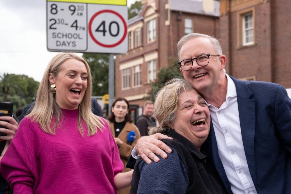 Opposition Labor Party leader Anthony Albanese (R) is greeted by a supporter as his partner Jodie Haydon (L) looks on during Australia's general election at a polling station in the suburb of Marrickville in Sydney on May 21, 2022. (Photo by Wendell Teodoro / AFP)