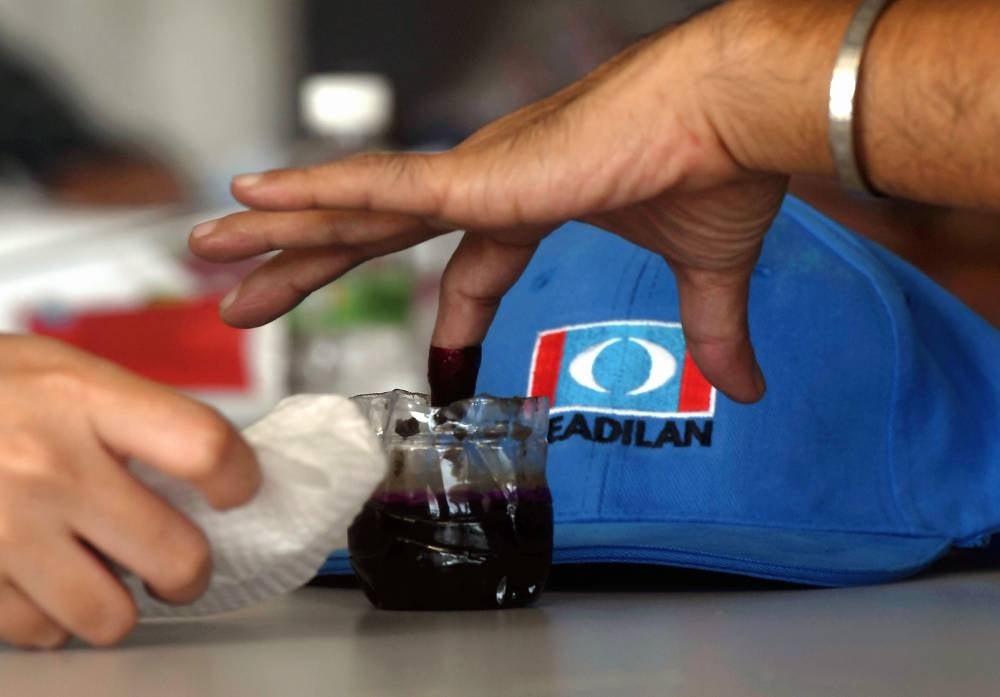 A voter dip his index finger into the election ink before the PKR polls. Photo - BERNAMA