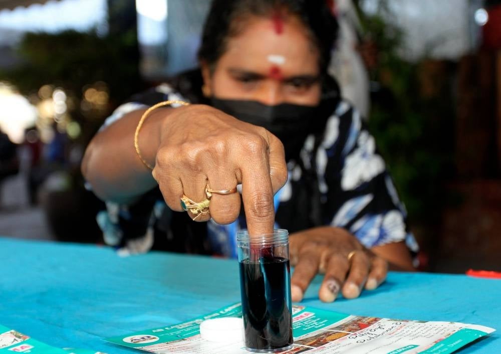 A PKR member dips finger in indelible ink during the voting process in the PKR 2022 party election in Bercham, on Sunday. - Photo: BERNAMA