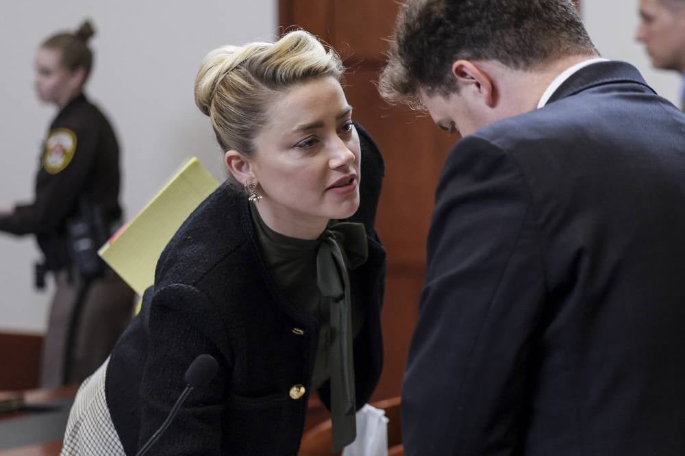 Actress Amber Heard speaks to her legal team as she leaves the courtroom for a break during US actor Johnny Depp's defamation trial against her, at the Fairfax County Circuit Courthouse in Fairfax, Virginia, on May 25, 2022. - AFP