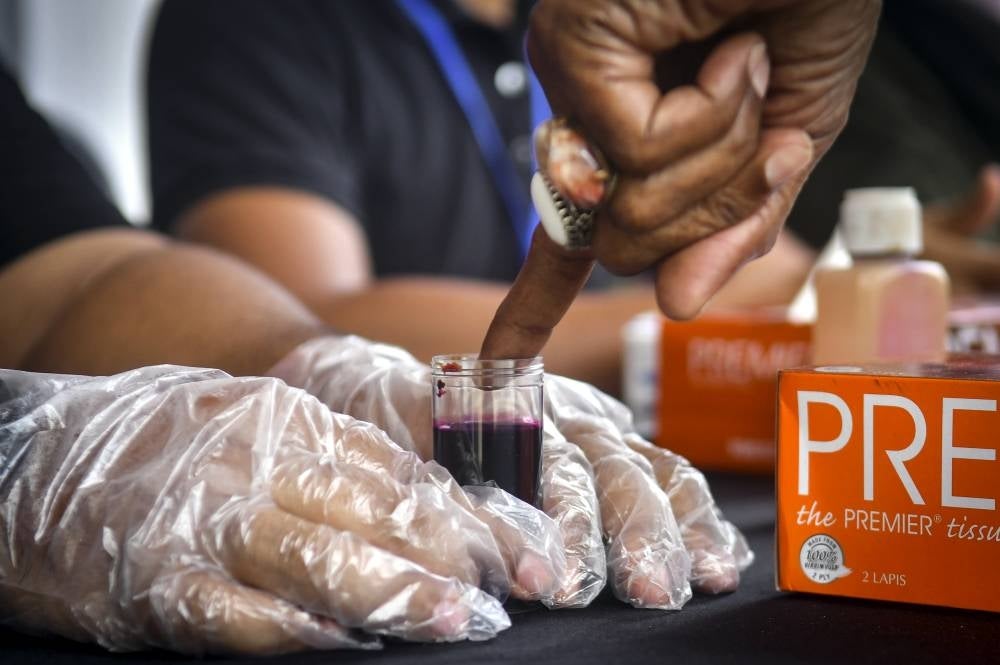 A PKR member dips finger in indelible ink during the voting process in the PKR 2022 party election in Marang. - Photo: BERNAMA