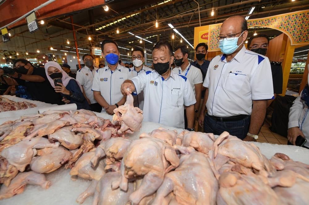 Domestic Trade and Consumer Affairs Minister Datuk Seri Alexander Nanta Linggi (two, right) observing the chickens sold at a market on May 26, 2022. - BERNAMA