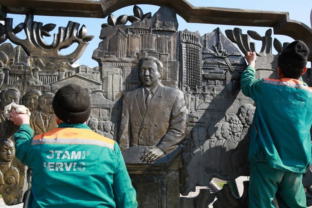Municipal workers polish a relief sculpture depicting former president Nursultan Nazarbayev outside the city hall in Almaty on March 1, 2020. (Photo by Ruslan PRYANIKOV / AFP)