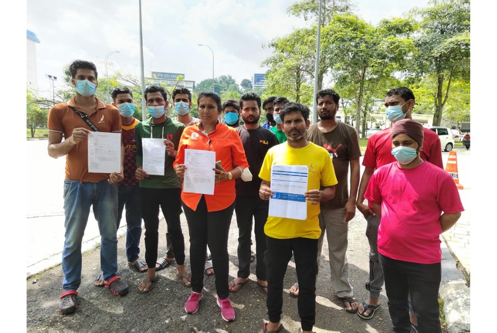 Twelve foreign workers and Rakvinder Kaur (middle) after lodging a third police report at IPD Shah Alam after their employer refused to return passports.