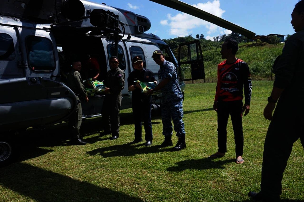 Deputy Works Minister, Arthur Joseph Kurup receives food items from two RMAF helicopters at Kampung Pangaraan, Nabawan