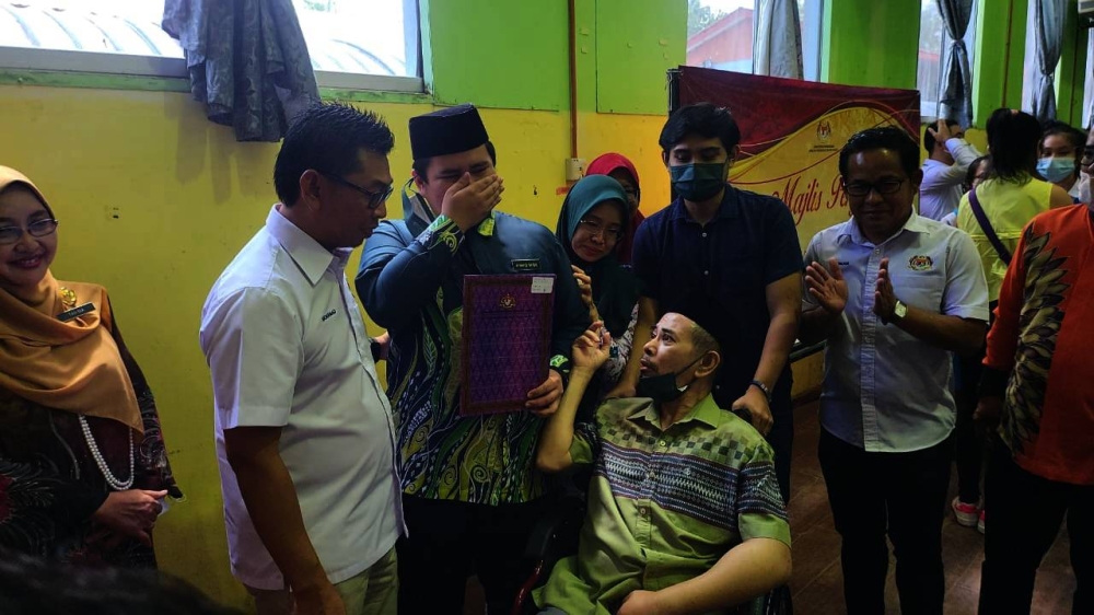 Ahmad Nabil receiving his SPM certificates witnessed by his father who had suffered a stroke. Photo: SINAR HARIAN
