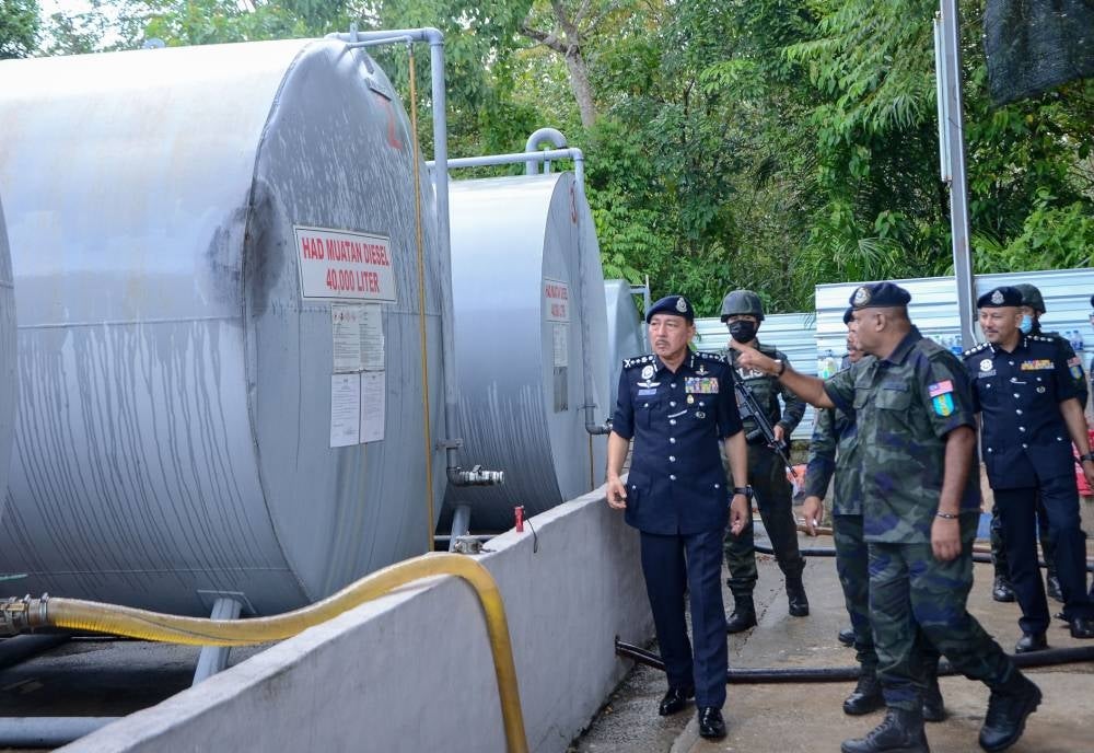 Kelantan acting police chief Datuk Muhamad Zaki Harun (left) visiting the location where the diesel was seized in Kampung Tebing Tinggi on Sunday. - BERNAMA