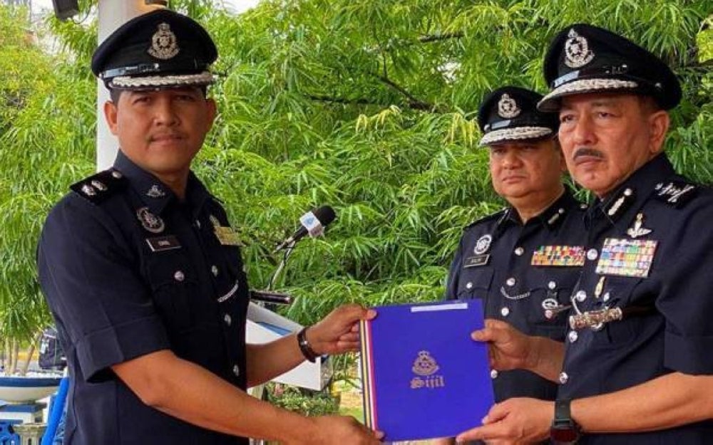 Acting Kelantan Police Chief Muhamad Zaki Harun (right) giving a letter of appreciation to Superintendant Mohamad Ismail, Bachok Chief of Police,