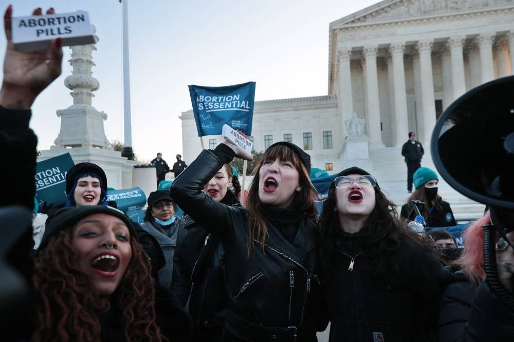 WASHINGTON, DC - (L-R) Alana Edmondson, Lila Bonow, Amelia Bonow, Aiyana Knauer celebrate after takiong abortion pills while demonstrating in front of the U.S. Supreme Court as the justices hear hear arguments in Dobbs v. Jackson Women's Health, a case about a Mississippi law that bans most abortions after 15 weeks, on Dec 1, 2021 in Washington, DC. (Photo by CHIP SOMODEVILLA/ AFP)