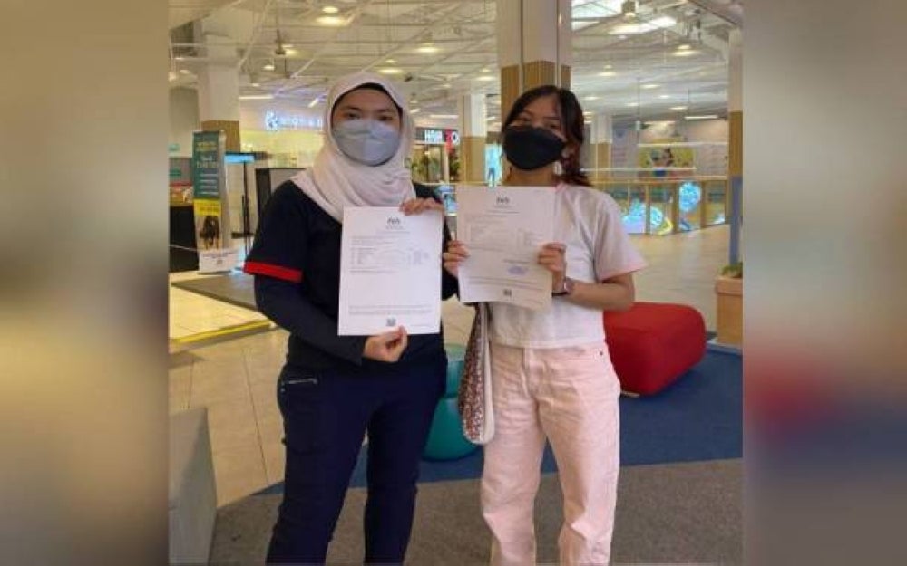 Nur Qamarina (left) and Nur Adeela showing their SPM result slips.