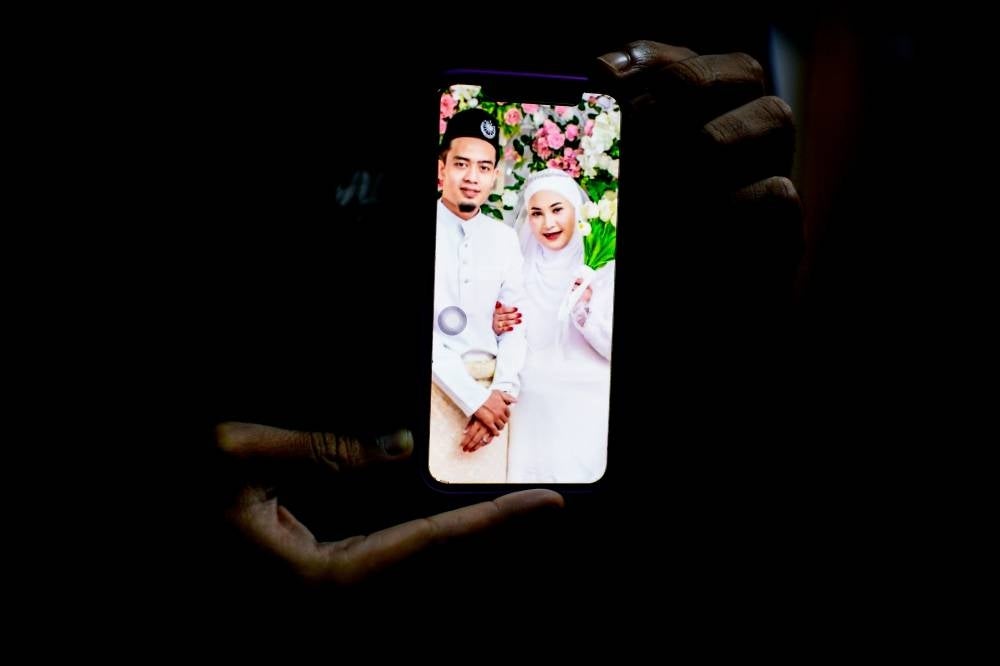 Khairul Ashraf Nor Azman, 24, showing a photo of him and his wife Nurul Hanis Abu Hassan, 23, who was four months pregnant. Nurul Hanis' body was found under a pile of tree trunks by the Kedah Fire and Rescue Department at about 9.30am on Tuesday. - Photo: BERNAMA