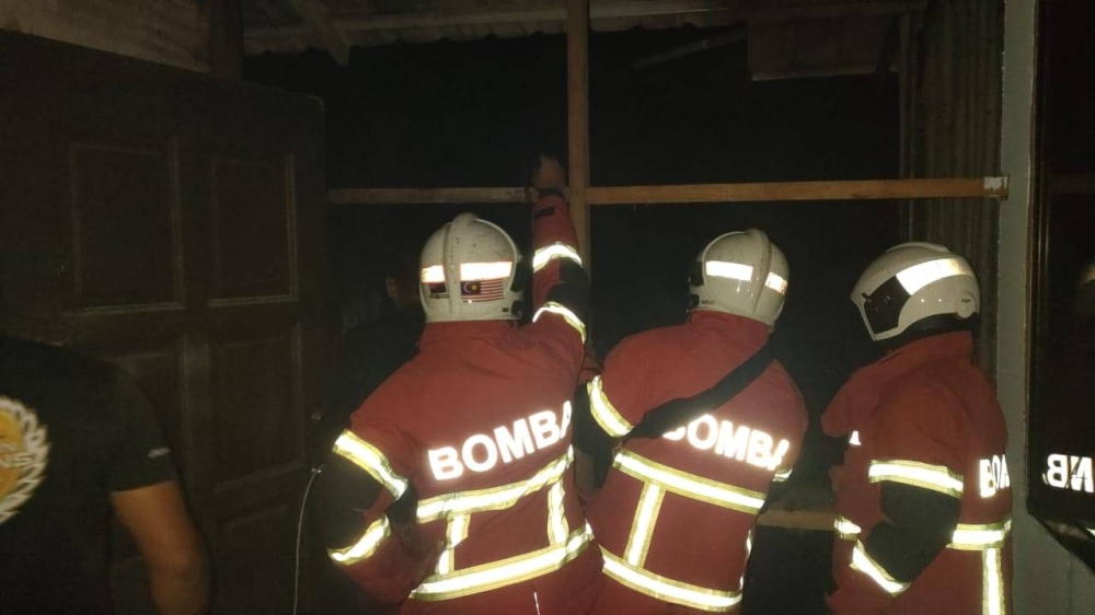Firemen monitoring the location of the fire involving a house on the water in Kampung Lok Urai, Pulau Gaya, Kota Kinabalu.