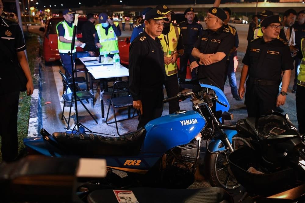 Deputy director-general (Planning and Operations) Aedy Fadly Ramli (left) inspecting a motorcycle which was seized during the Hari Raya Aidiladha Special Op at the Sungai Besi toll plaza, last night. - BERNAMA