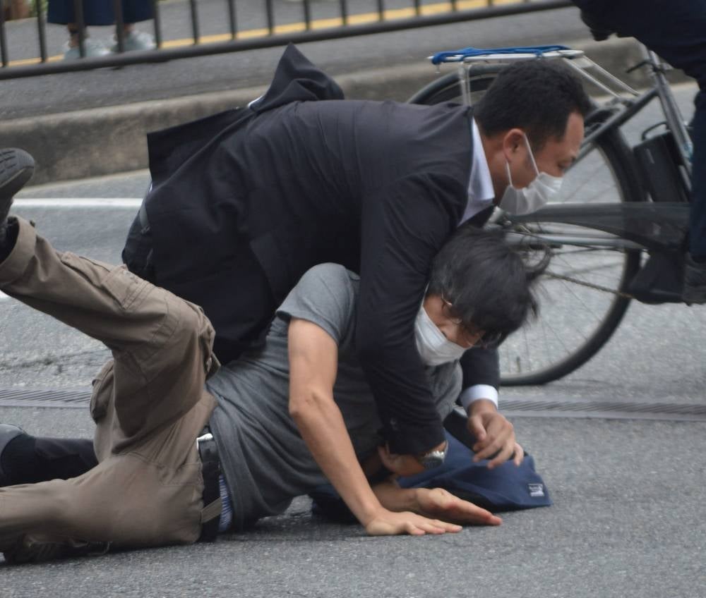 A man (bottom) suspected of shooting former Japanese prime minister Shinzo Abe is tackled to the ground by police at Yamato Saidaiji Station in the city of Nara on July 8, 2022. (Photo by Yomiuri Shimbun / AFP)