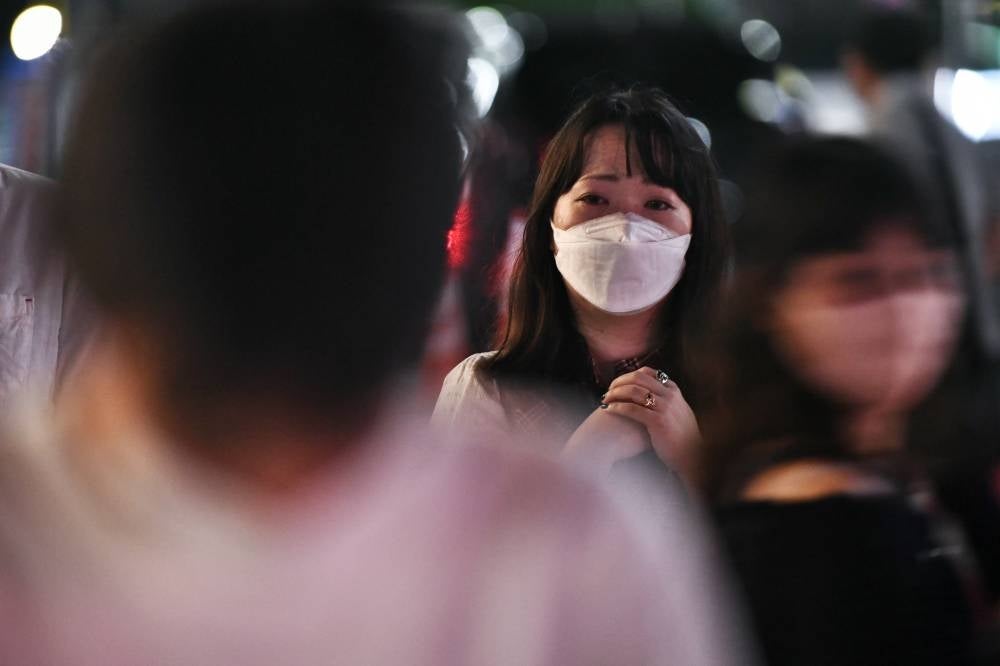 People pay their respects in front of a makeshift memorial outside Yamato-Saidaiji Station, where former Japanese prime minister Shinzo Abe was shot earlier in the day, in Nara on July 8, 2022. - (Photo by Philip FONG / AFP)