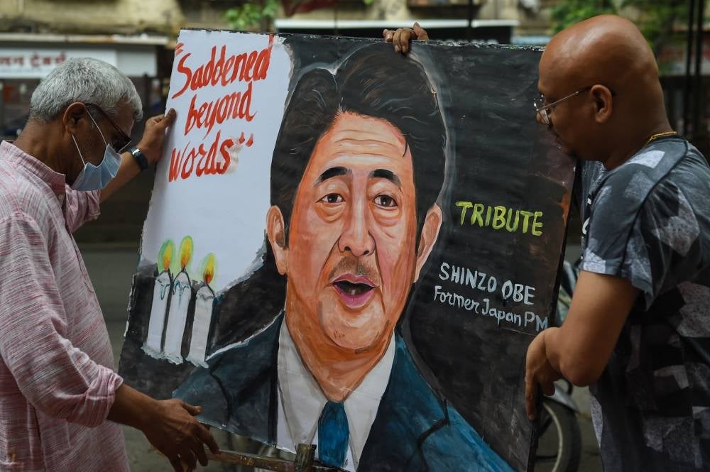 Artists carry a painting of former Japanese prime minister Shinzo Abe, in Mumbai on July 8, 2022, to pay tribute following his death after he was shot at a campaign event in the Japanese city of Nara. (Photo by Punit PARANJPE / AFP)