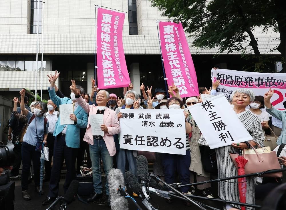 Plaintiffs in the Tokyo Electric Power Company (TEPCO) shareholder derivative suit, brought by shareholders over the nuclear disaster triggered by the 2011 tsunami, react following the court's decision outside the Tokyo District Court on July 13, 2022. (Photo by JIJI PRESS / AFP) 