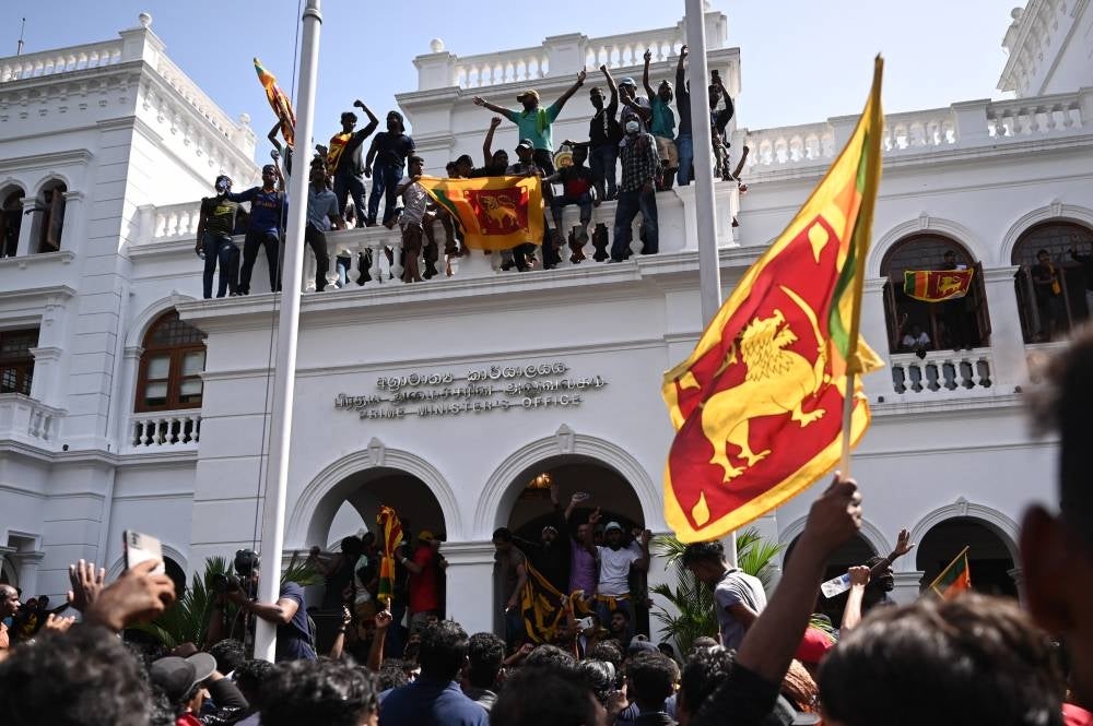 Demonstrators shout slogans and wave Sri Lankan flags during an anti-government protest inside the office building of Sri Lanka's prime minister in Colombo on July 13, 2022. Photo: AFP/ Arun Sankar