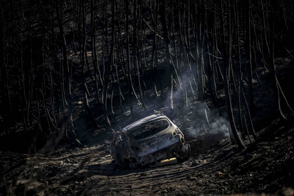This photograph shows a burnt car where two people reportedly lost their lives trying to flee the flames during a wildfire, in the village of Penabeice in Murca, north of Portugal, on July 20, 2022. (Photo by PATRICIA DE MELO MOREIRA / AFP)