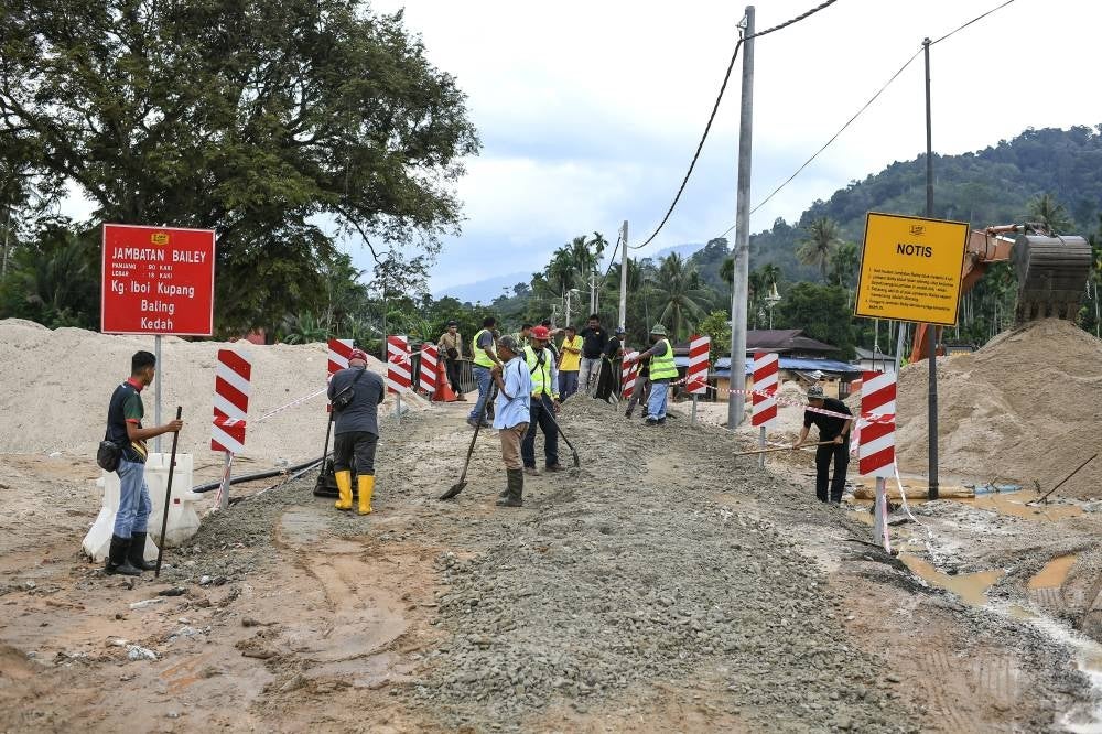 Public Works Department staff doing road works following a flood incident due to continuous heavy rains in Baling, today. - BERNAMA