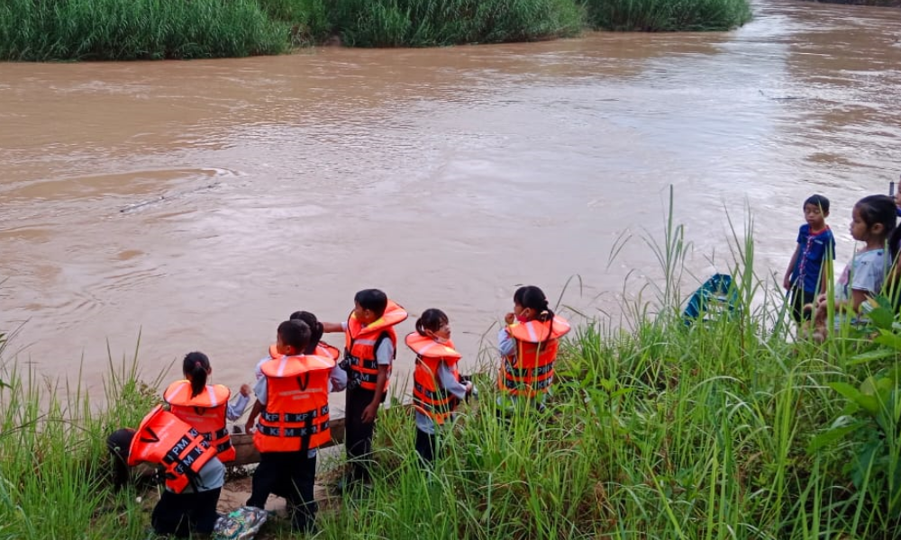 Pupils wearing life jackets waiting for their turns to cross the river by boat to get to school.