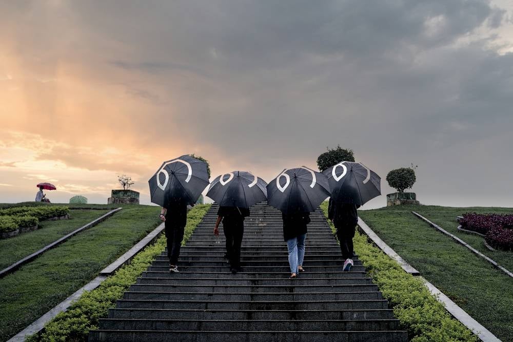 This handout picture taken and released by Yangon People's Strike on August 8, 2022, shows protesters walking through Yangon with umbrellas bearing in Burmese the number 8 during a rally to mark the anniversary of the August 8, 1988 democracy uprising against a previous junta. (Photo by Handout / Yangon People's Strike / AFP) 