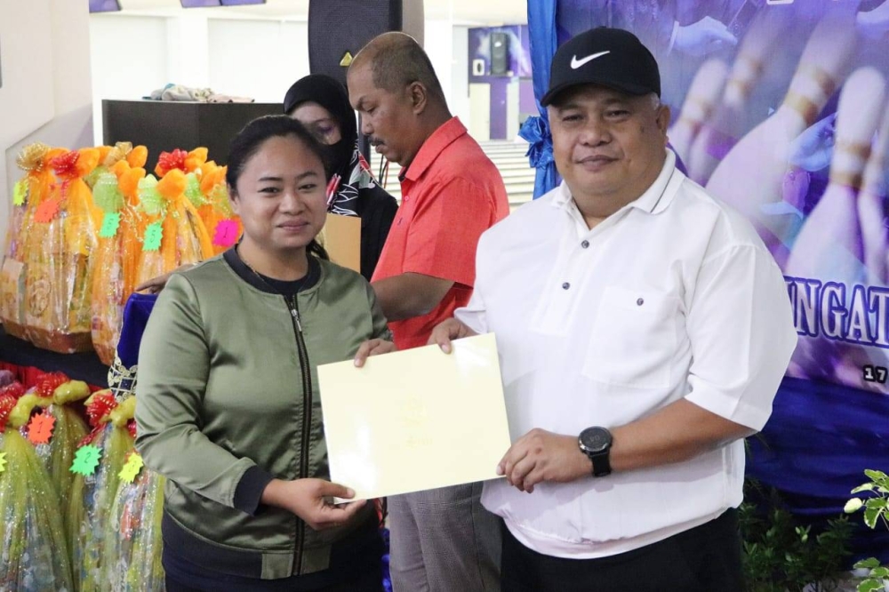 Idris (right) presenting a certificate of appreciation to one of the media practitioners who competed in the bowling tournament in conjunction with the 215th Police Day. 