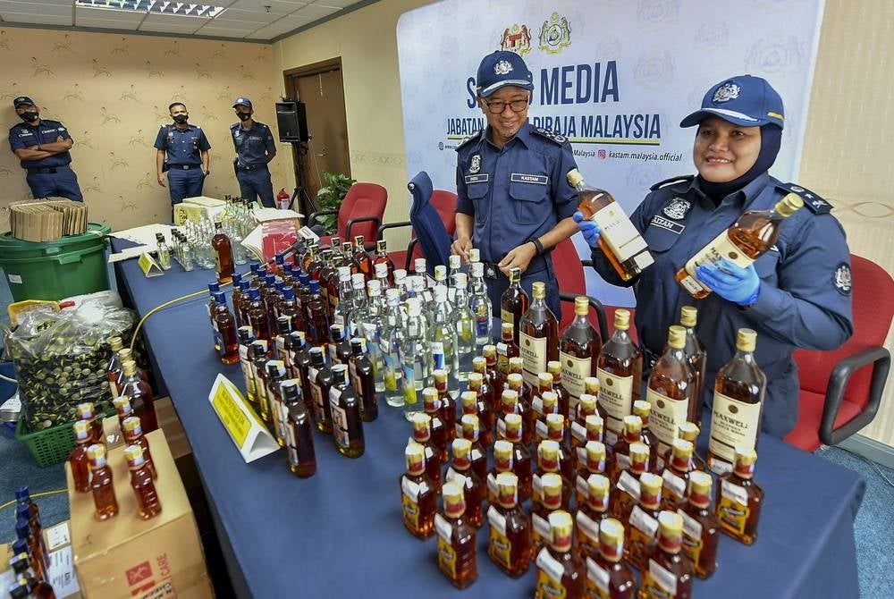 Customs director-general Datuk Zazuli Johan (second from right) with another customs officer showing the confiscated liquor - BERNAMA Photo