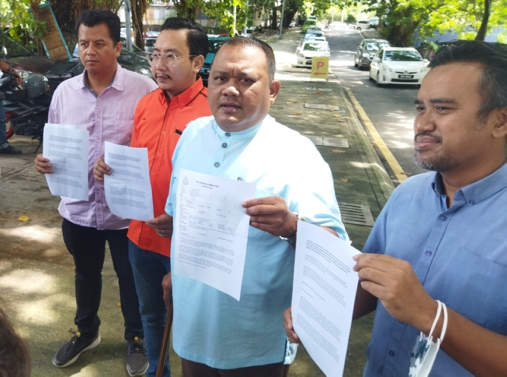 Mohd Sany (second, right) showing a copy of the police report during a press conference in front of Dang Wangi district police headquarters on Monday.