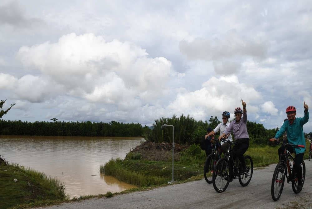 Deputy Minister of The Environment and Water Ministry (Kasa) Datuk Mansor Othman (middle) with Penaga State Assemblyman Mohd Yusni Mat Piah (right) and Department of Irrigation and Drainage (DID) Deputy Director-General (Business Sector) Datuk Ir Sabri Abdul Mulok (left) riding bicycles on the banks of Sungai Muda in Kampung Permatang Bendahari after officiating the National River Trail Project (DSK) today - Bernama Photo