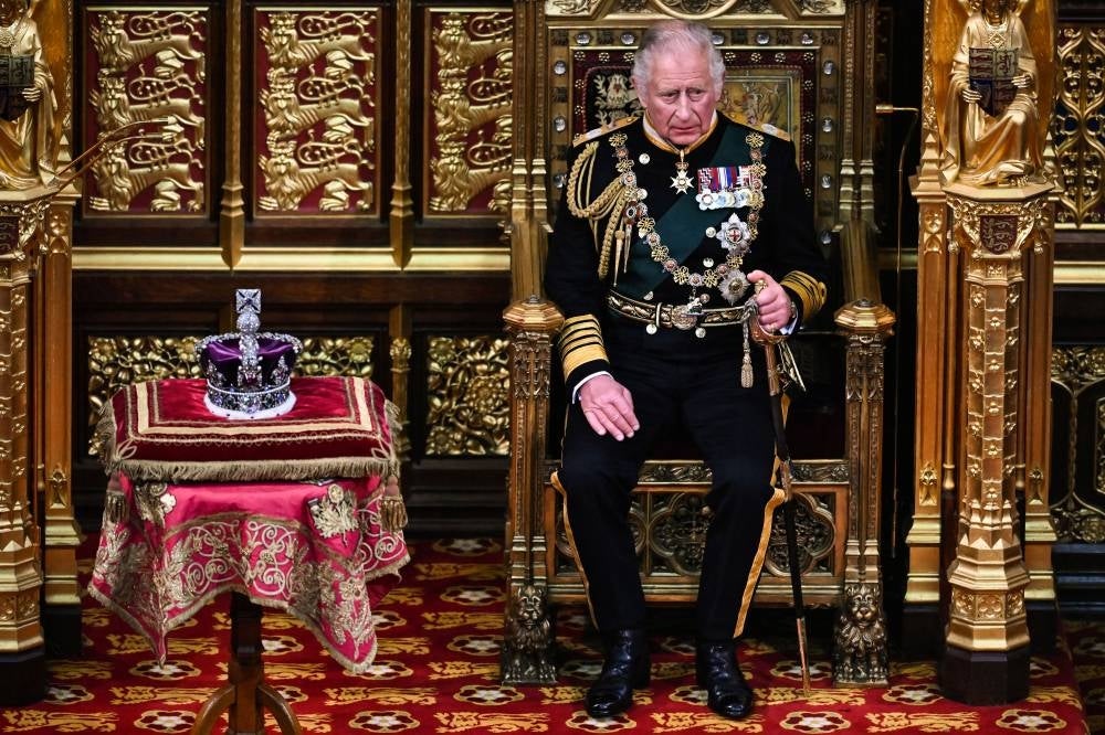In this file photo taken on May 10, 2022 Britain's Prince Charles, Prince of Wales (R) sits by the The Imperial State Crown (L) in the House of Lords Chamber, during the State Opening of Parliament, in the Houses of Parliament, in London. (Photo by Ben Stansall / POOL / AFP)