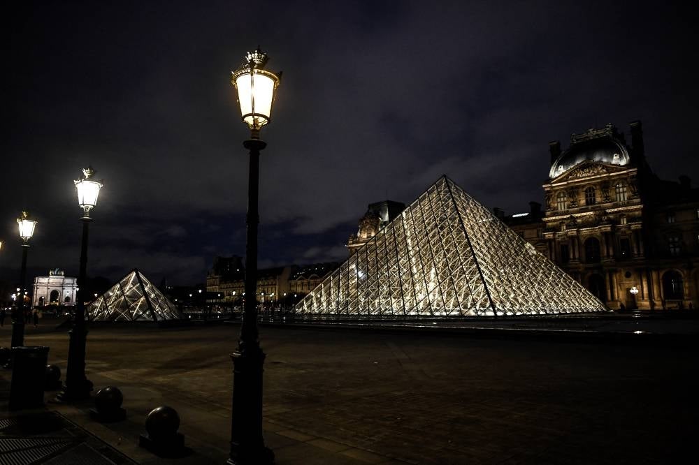 This file photograph taken on Oct 29, 2020, shows an exterior view of the illuminated Musee du Louvre and The Pyramide du Louvre, in Paris, designed by Ieoh Ming Pei. (Photo by STEPHANE DE SAKUTIN / AFP) 