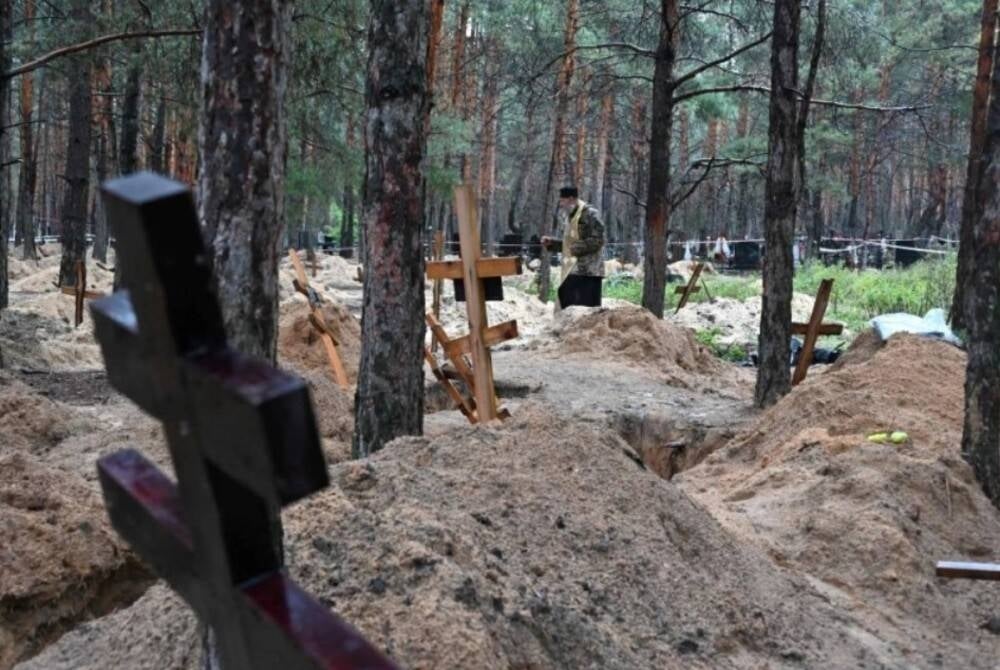 An Orthodox priest holding a thurible while serving among graves in a forest near Izyum where Ukrainian investigators uncovered more than 440 graves after the city was recaptured from Russian forces - AFP Photo