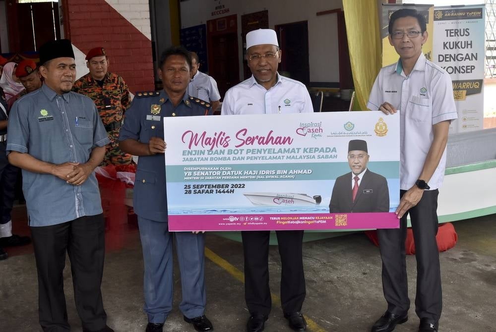 Minister in the Prime Minister's Department (Religious Affairs) Senator Datuk Idris Ahmad at the Tawau Fire and Rescue Station witnessed the handing over of a replica check from acting Yapeim director-general Awang @ Musran Tawil (right) to the Tawau Zone Fire Superintendent Jasri Ab Jal (third from left) at the handover ceremony - Bernama photo