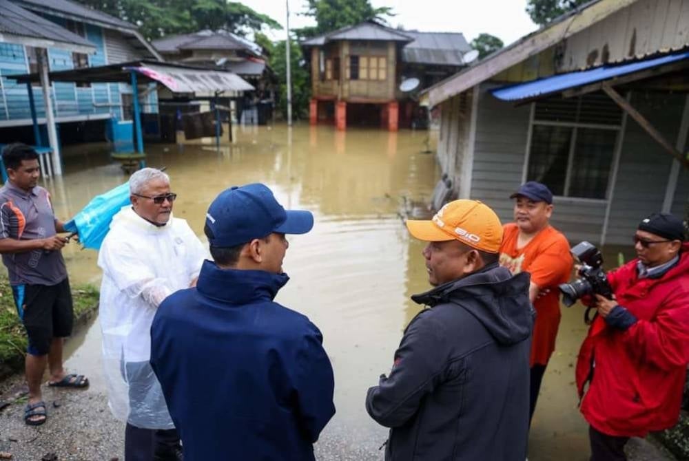 Norazam (two, left) with Johor Menteri Besar Datuk Onn Hafiz Ghazi (three, left) observing the condition of Kampung Mohd Amin that was flooded on Sunday.