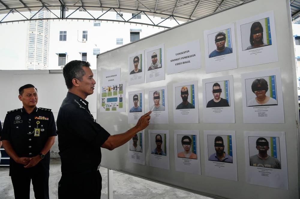 Mohd Shuhaily (right) shows the 14 suspects detained after being involved in a nude video blackmail syndicate via social media during a press conference at the State Contingent Police Headquarters today. - Bernama Photo