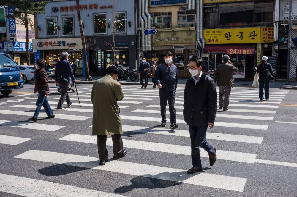 Pedestrians walk across a road in Seoul on April 8, 2022. - (Photo by ANTHONY WALLACE / AFP)