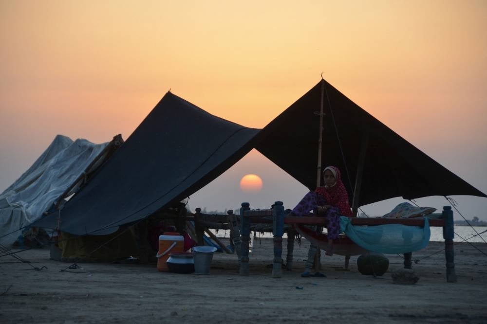 Pakistan: An Internally displaced flood-affected girl sits in her tent at sunset at a camp in the flood-hit area in Dera Allah Yar in Jaffarabad district of Balochistan province on Sept 28, 2022. (Photo by Fida HUSSAIN / AFP)