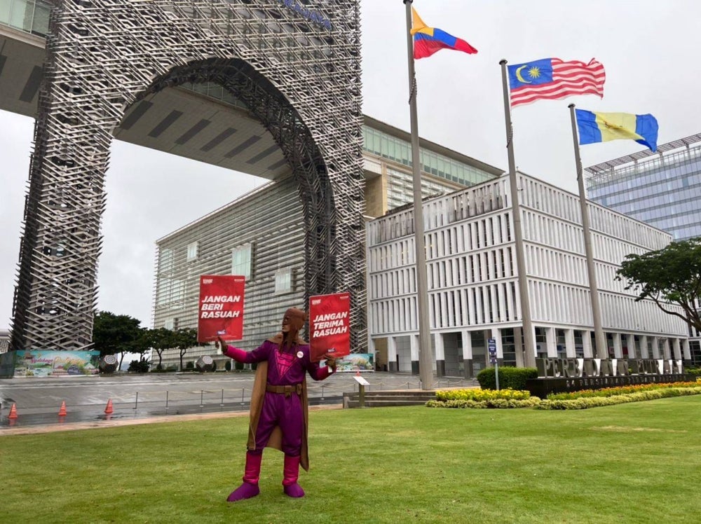 Keluang Man holds anti-corruption banners.