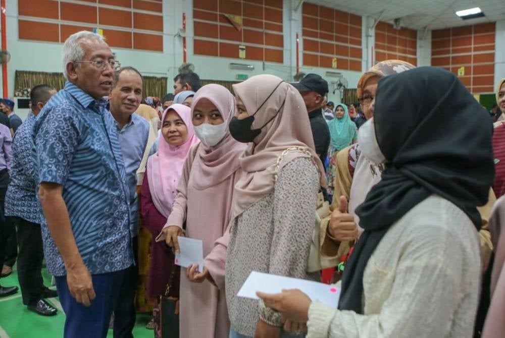 Mahdzir (left) giving out donations to students from public institutions of higher education at Kuala Nerang