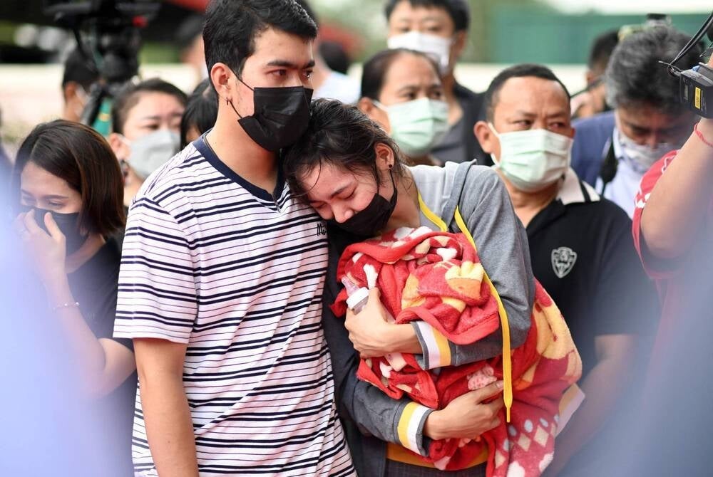 The mother of a victim holds a milk bottle while standing outside the nursery in Na Klang, Thailand, the day after a former police officer killed at least 37 people in a mass shooting at the site - Photo by Manan VATSYAYANA / AFP