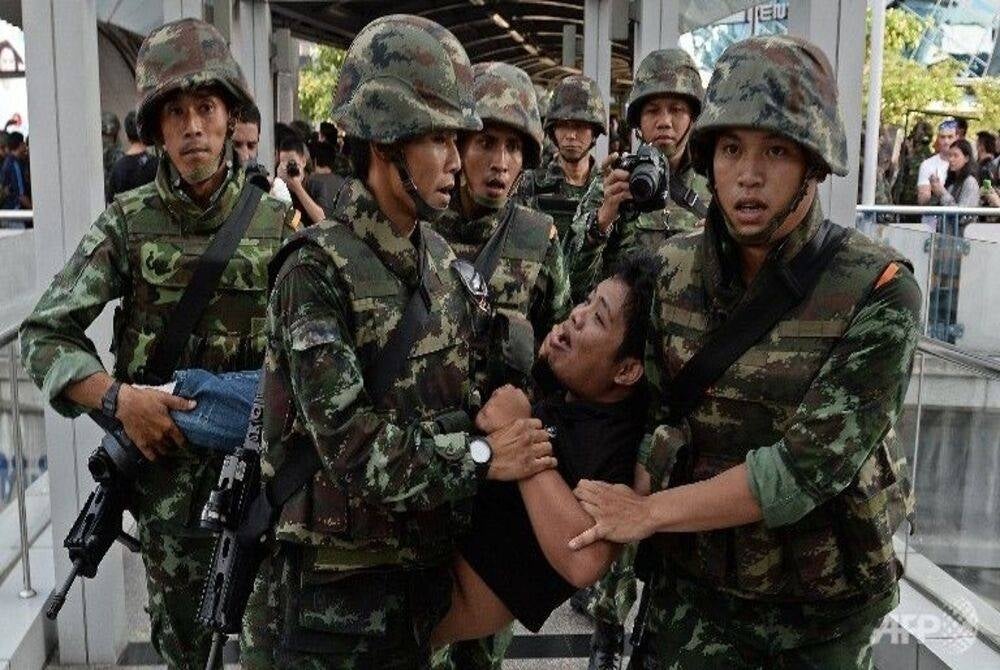 An anti-coup protester is taken away by soldiers - Photo by AFP/Christophe Archambault