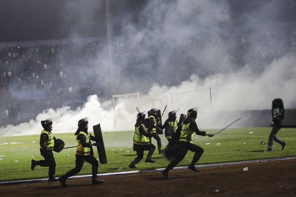 Police officers run as they try to stop soccer fans from entering the pitch during a clash between fans at Kanjuruhan Stadium in Malang, East Java, Indonesia on Oct 2, 2022. - EPA