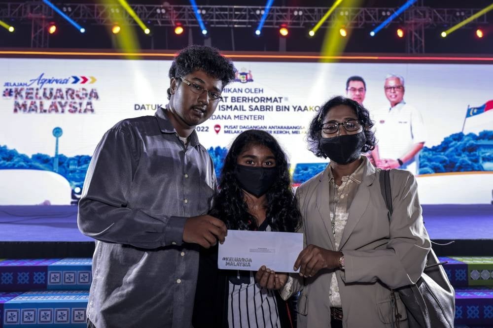 Recipients of assistance from Yayasan Keluarga Malaysia D H J Taanush Pillai, 16, (left) and his sister D H J Hemashreya Pillai, 12, (middle) who lost their father due to Covid-19 with their mother M. Sumathy (right). - BERNAMA