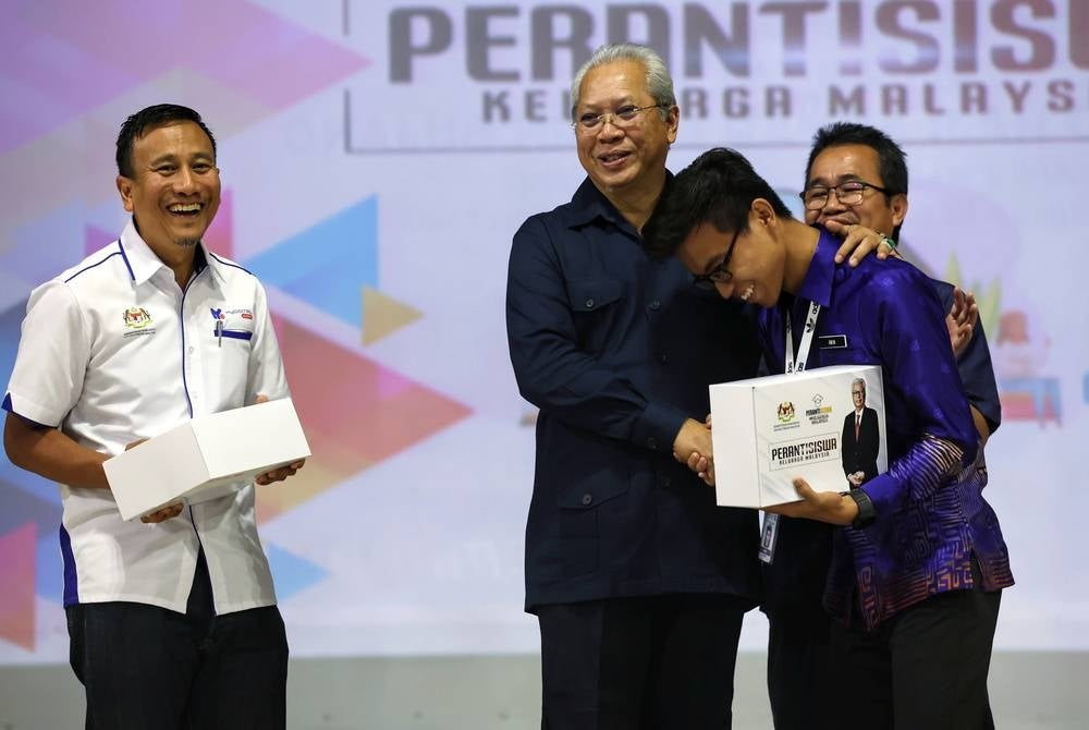 Communications and Multimedia Minister Tan Sri Annuar Musa (second from right) handing over student devices to students - BERNAMA