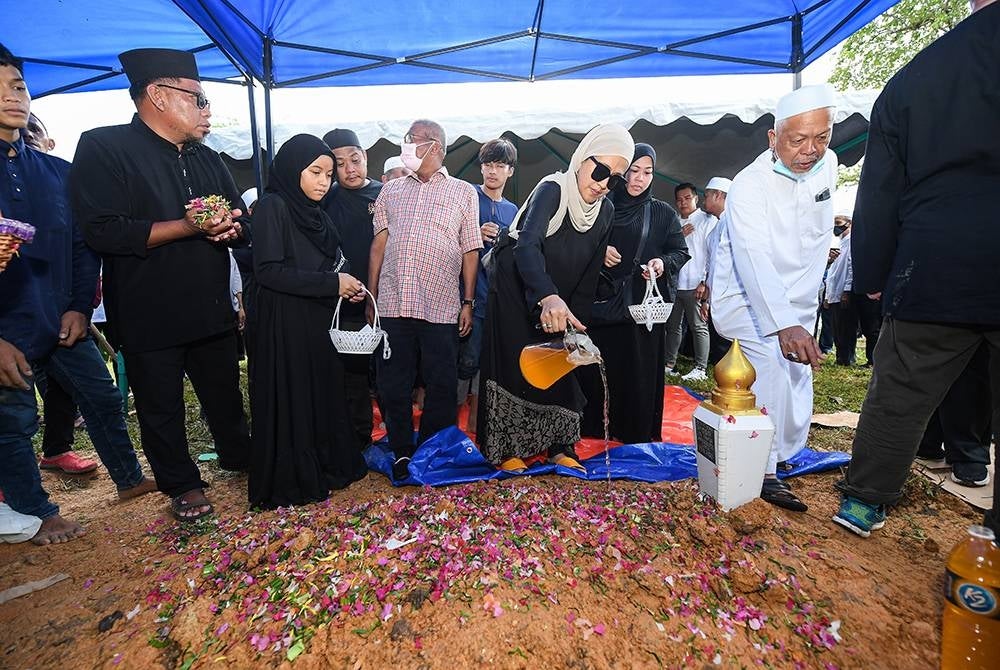 Shamidah Elissawaty Samsudin poured water on her father's grave at Kampung Sungai Kayu Muslim Cemetery today. - Bernama Photo