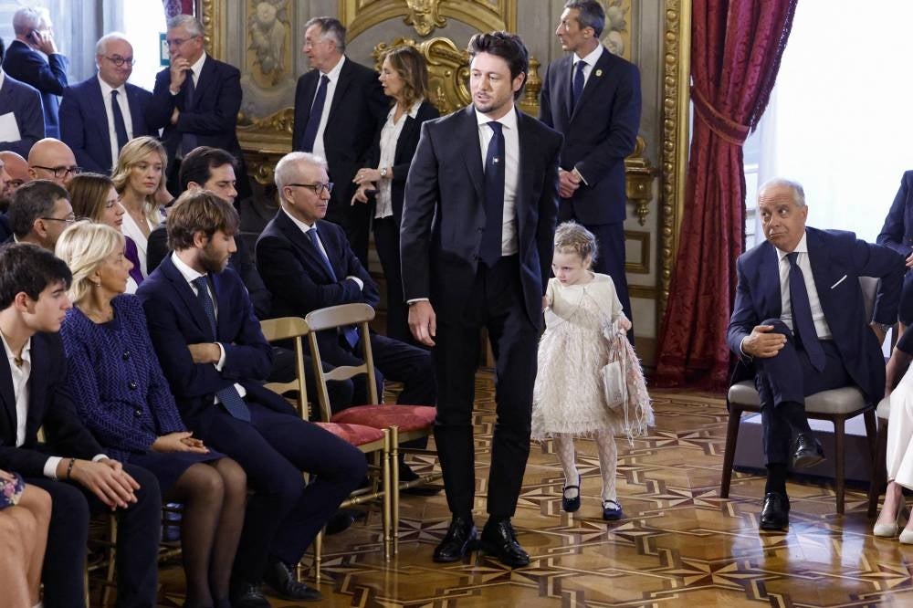Andrea Giambruno (C), partner of Italy's new Prime Minister Giorgia Meloni, and her daughter attend the swearing-in ceremony of the new Italian Government at the Quirinal Palace in Rome on October 22, 2022. (Photo by FABIO FRUSTACI / ANSA / AFP) 