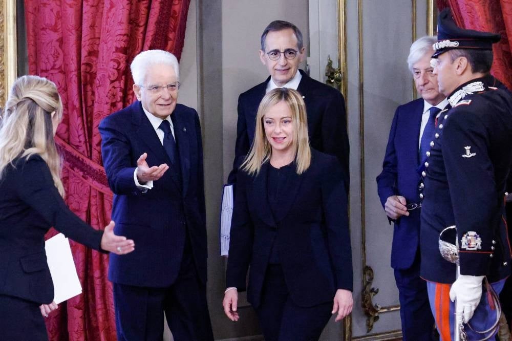 Italian President Sergio Mattarella (2nd L) welcomes new Prime Minister Giorgia Meloni (C) as she arrives for the swearing-in ceremony of the new Italian Government at the Quirinal Palace in Rome on October 22, 2022. (Photo by FABIO FRUSTACI / ANSA / AFP) 